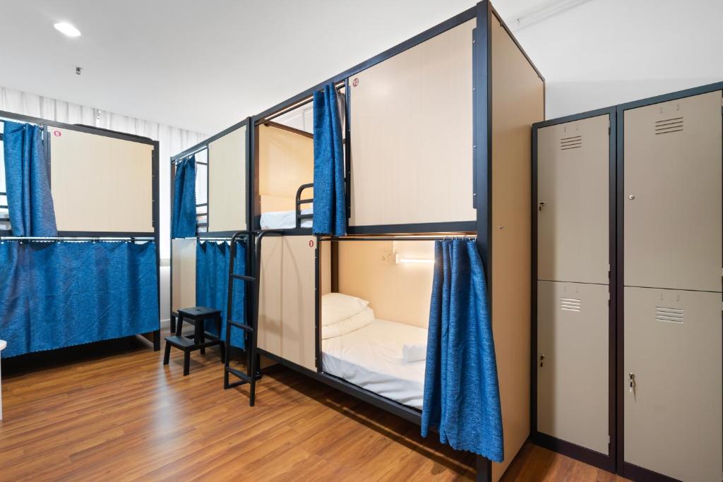 Habitación con 3 literas y cortinas azules. en Amethyst Dorm KLCC en Kuala Lumpur