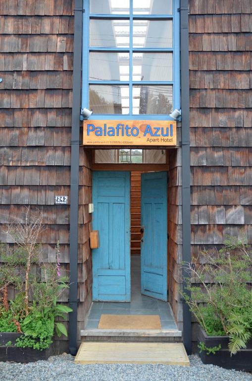 a building with blue doors and a sign on it at Palafito Azul Apart Hotel in Castro