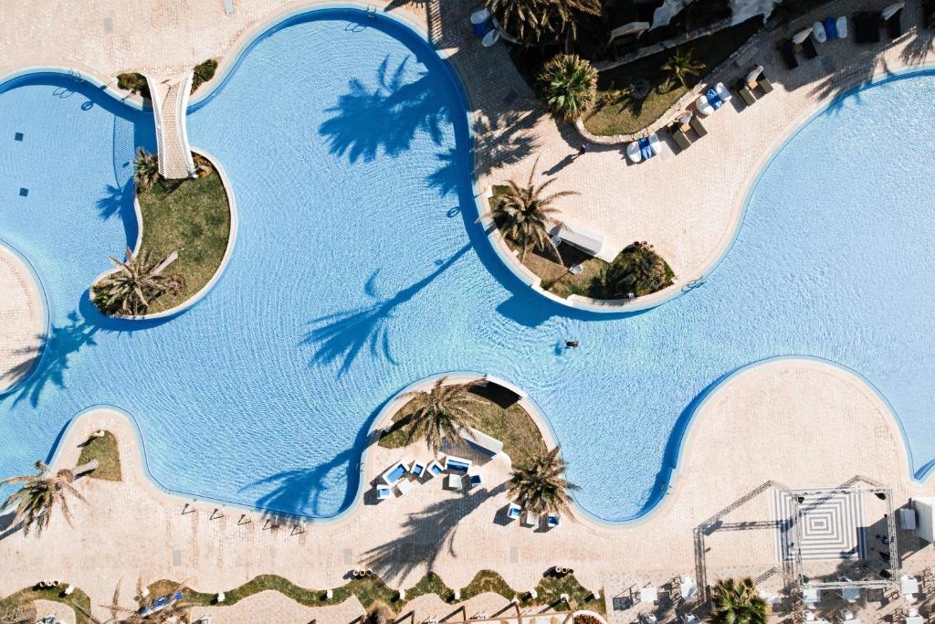 eine Aussicht über den Pool des Resorts mit Palmen in der Unterkunft ROBINSON DJERBA BAHIYA - All Inclusive in Midoun