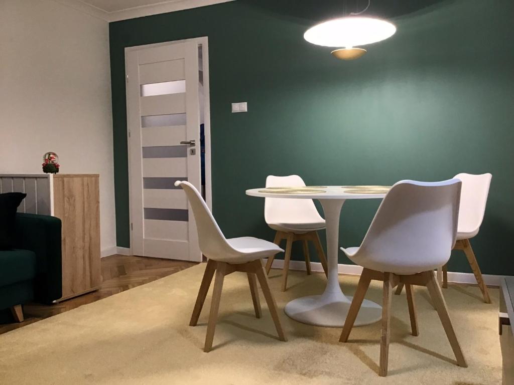 a table and chairs in a room with a green wall at Apartament Karpaty in Krynica Zdrój