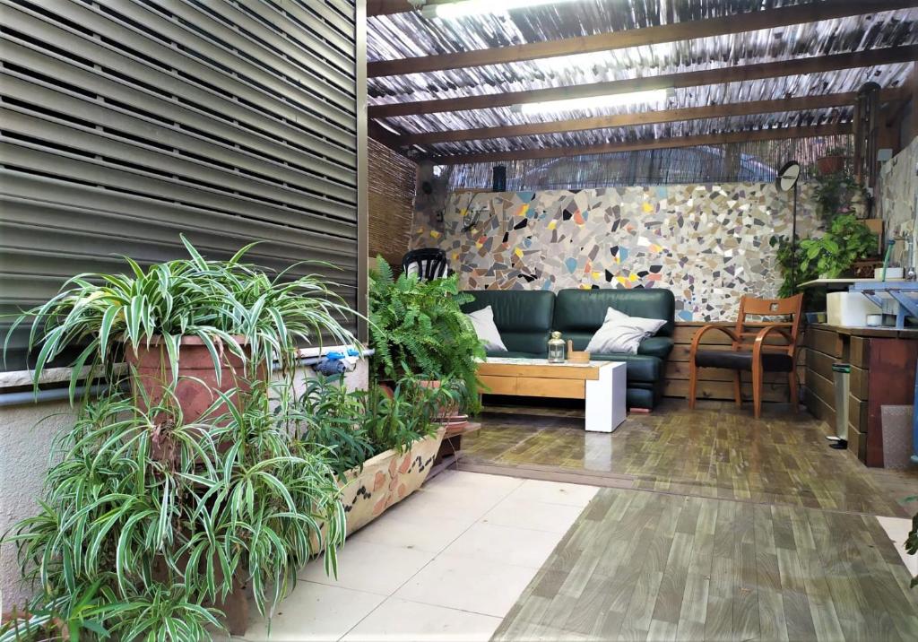 een lobby met planten en een bank in een kamer bij Ahuzat Shaul - Apartment in H̱adera