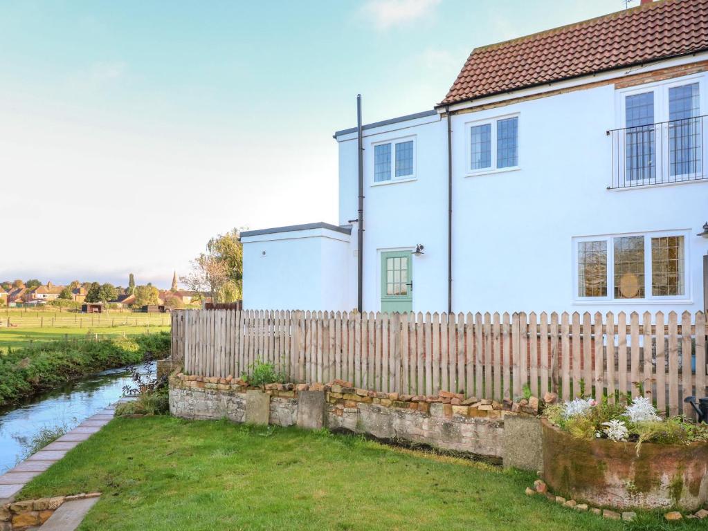 une maison blanche avec une clôture en bois et une cour dans l'établissement Mill Cottage, à Mansfield