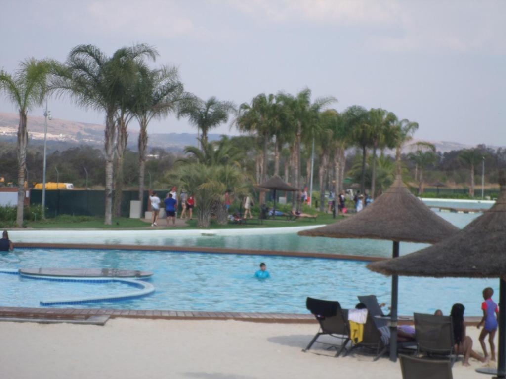 a swimming pool with palm trees and people in it at The Blyde Crystal Lagoon Cologne4 in Pretoria