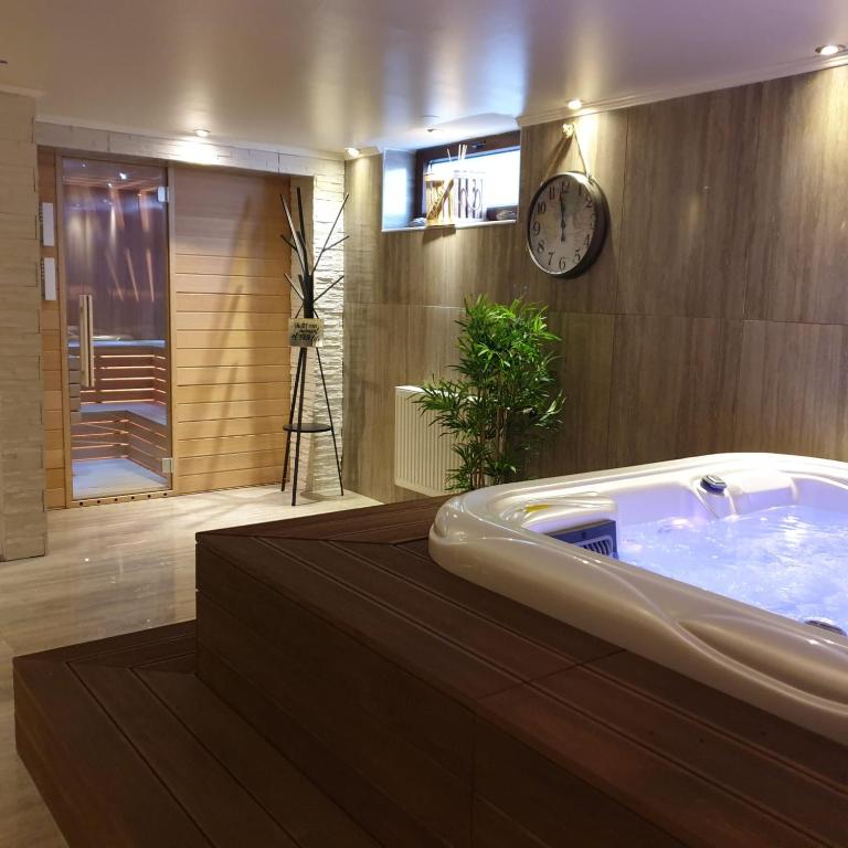 a bathroom with a tub and a clock on the wall at Villa Biser Dunava in Vukovar