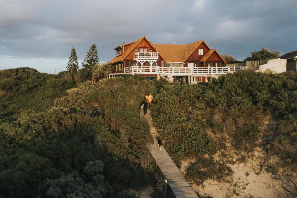 uma casa no topo de uma colina com um caminho para ela em Surf Lodge South Africa em Jeffreys Bay