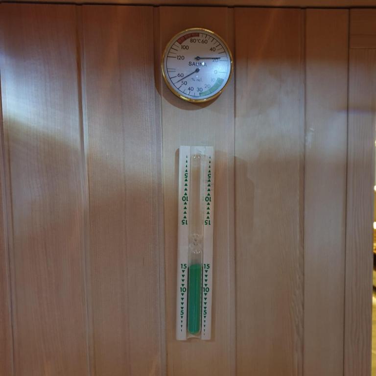 a clock and a thermometer hanging on a wall at Villa Biser Dunava in Vukovar