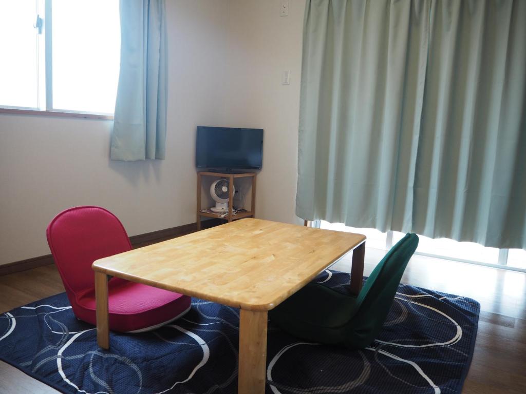 een kamer met een houten tafel en 2 stoelen bij Guesthouse Sea Turtle in Miyako Island