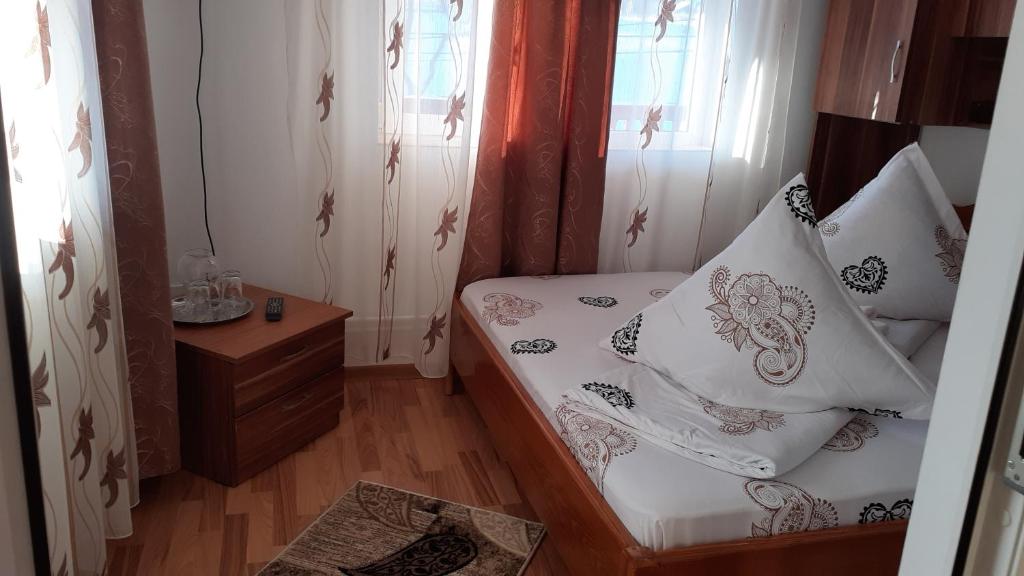a small room with a bed with white sheets and pillows at Casa Nicoleta in Gura Humorului