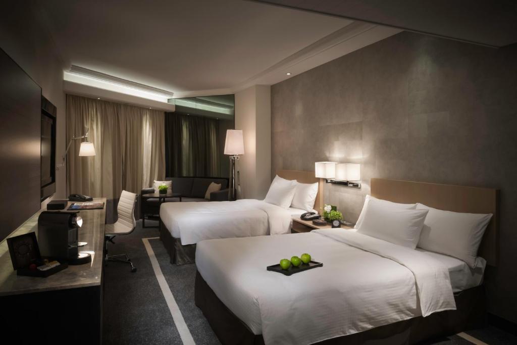 een hotelkamer met 2 bedden en een bureau bij Gateway Hotel, Marco Polo in Hong Kong