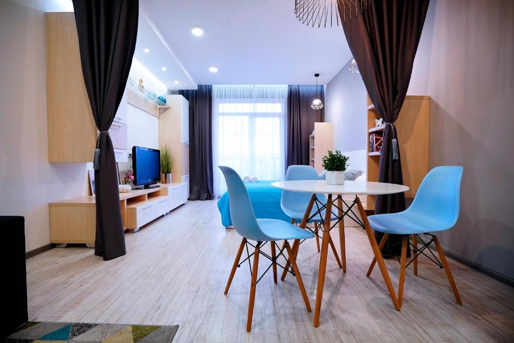 a living room with a table and blue chairs at British Quarter Studios in Kyiv