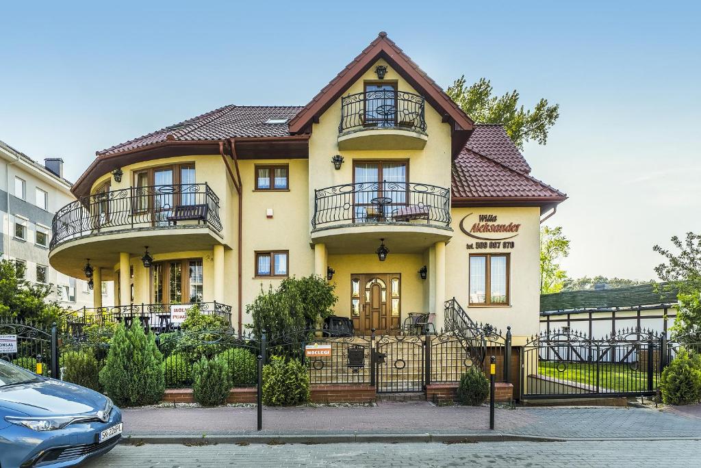 een geel huis met een hek ervoor bij Willa Aleksander in Władysławowo