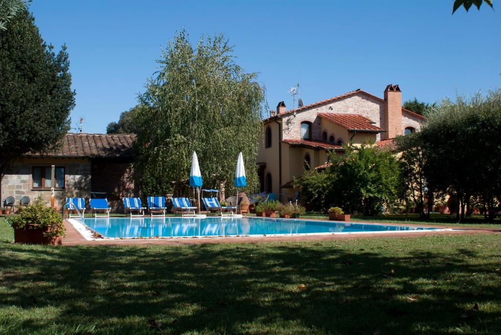 een zwembad met stoelen en parasols naast een huis bij Le Virtù in Migliarino