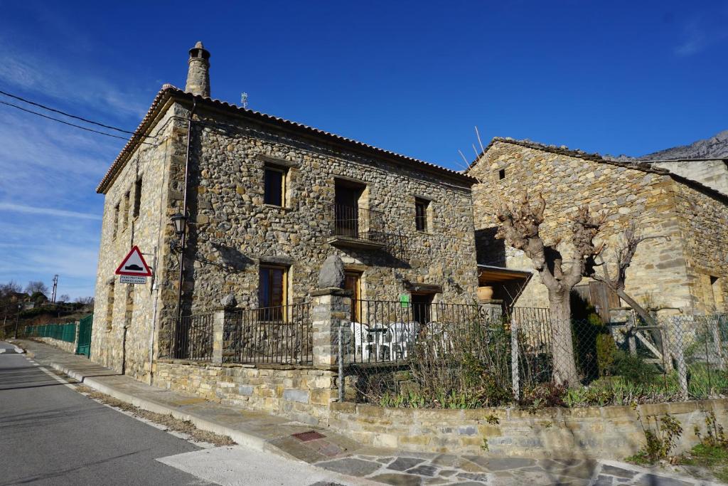 un antiguo edificio de piedra al lado de una calle en Casa Rural La Escuela, en Los Molinos