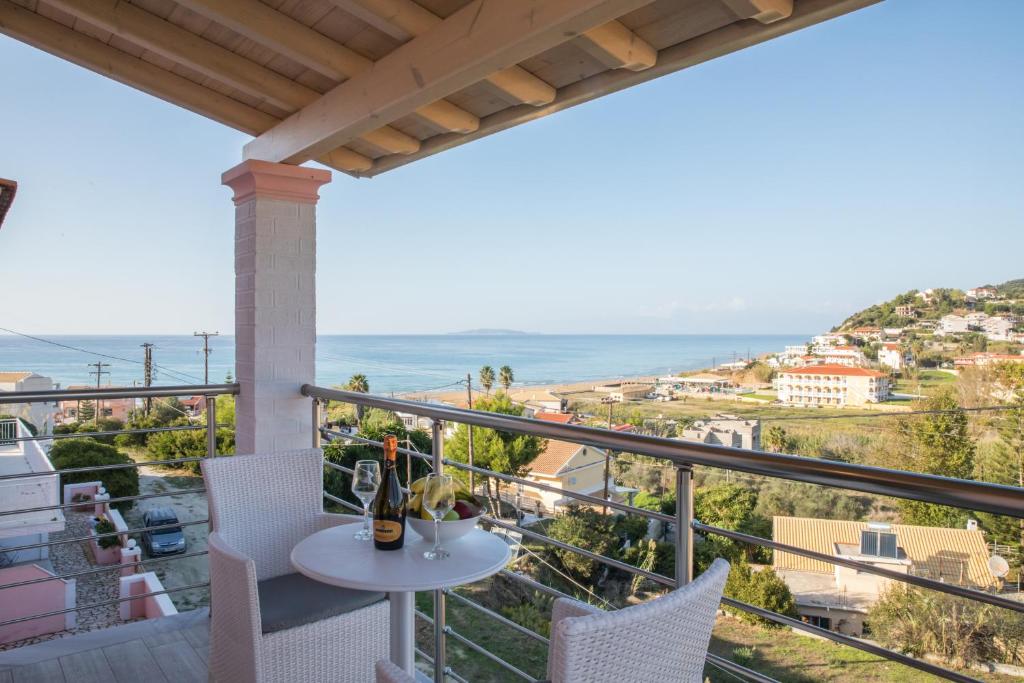 balcón con mesa, sillas y vistas al océano en Moros Apartments, en Agios Stefanos