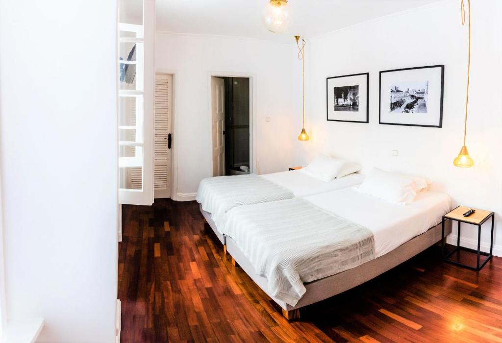 a white bedroom with a large bed and wooden floors at Comercial Azores Boutique in Ponta Delgada