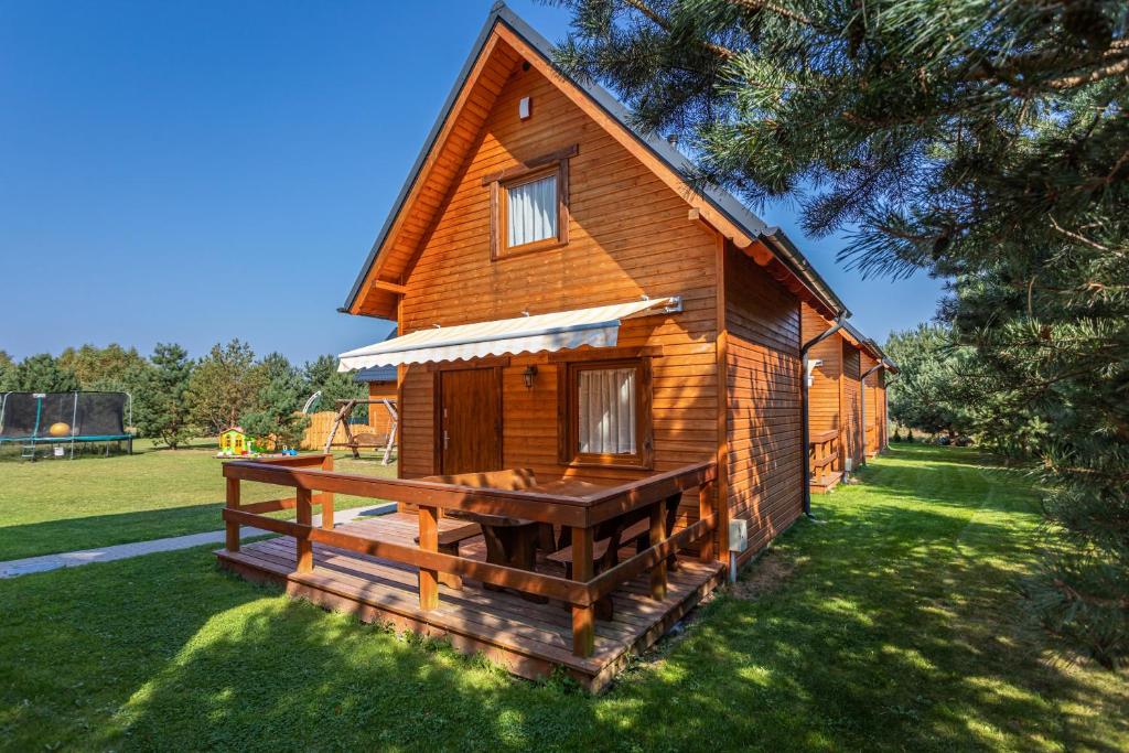 a large wooden cabin with a large deck in the grass at Domki Miłe. Lubiatowo in Lubiatowo