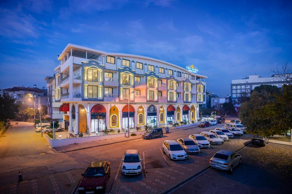 a large building with cars parked in a parking lot at The Sansa Hotel & Spa in Manavgat