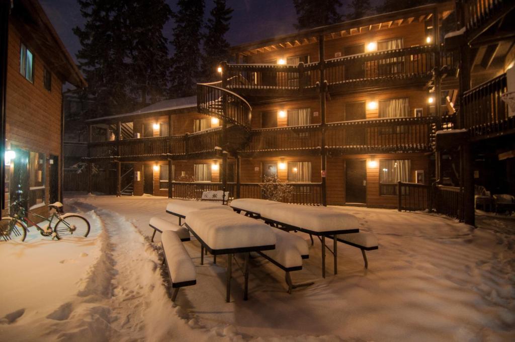 a group of benches covered in snow in front of a building at Banff International Hostel in Banff