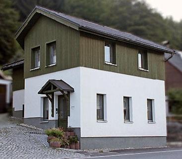 une maison verte et blanche sur le côté d'une rue dans l'établissement Ferienhaus Schreinert, à Breitenbrunn/Erzgeb.