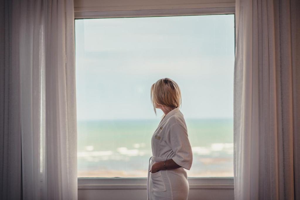 Una mujer con un traje parada frente a una ventana en Lucania Palazzo Hotel en Comodoro Rivadavia