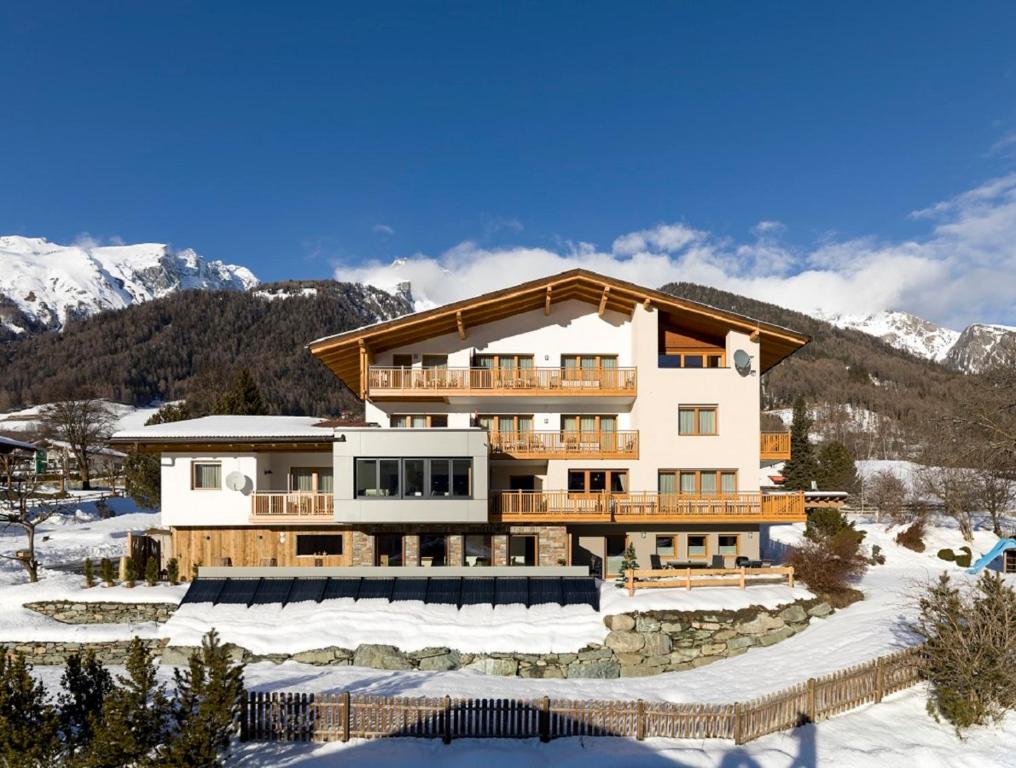 un grande edificio nella neve con le montagne di Haus Bstieler a Virgen