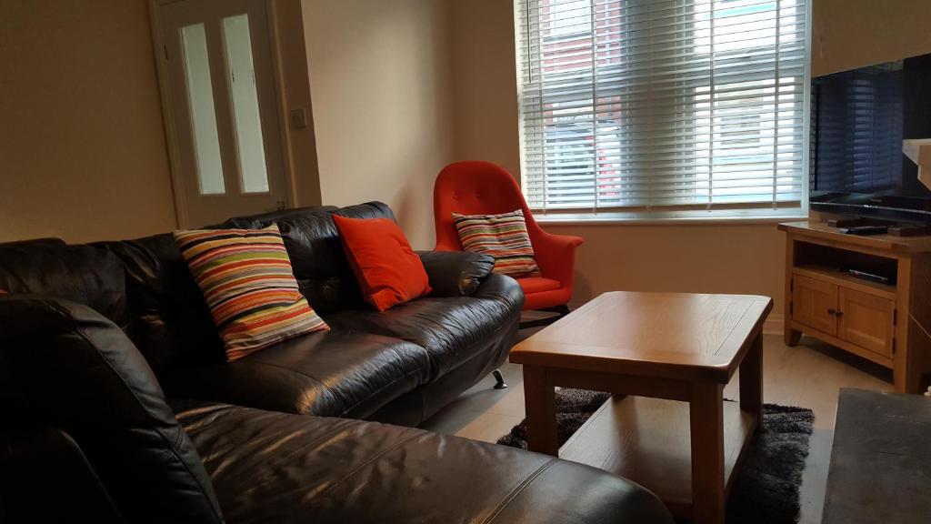 a living room with a leather couch and a table at 4 Bedroom House in Weymouth