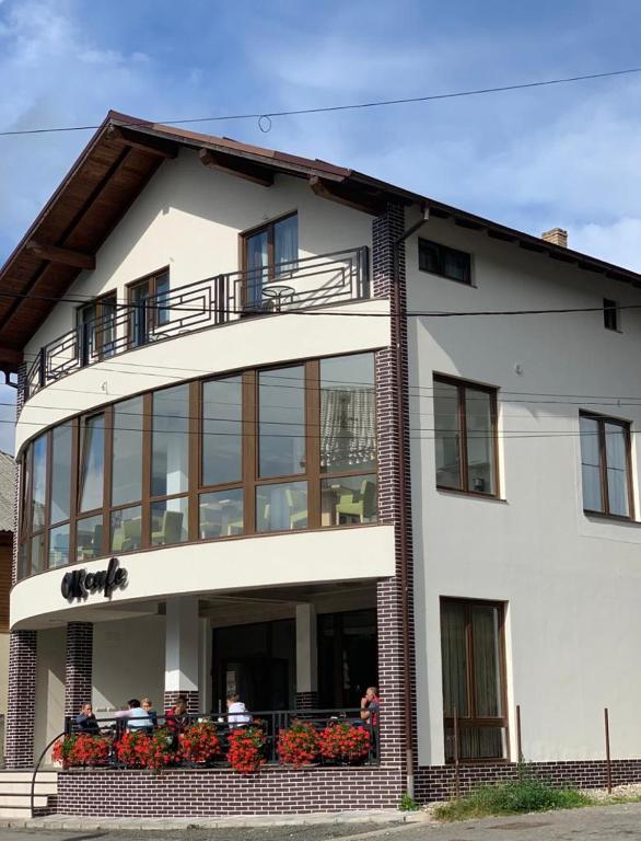 a large white building with people sitting on the balcony at Pensiunea OK in Vişeu de Sus