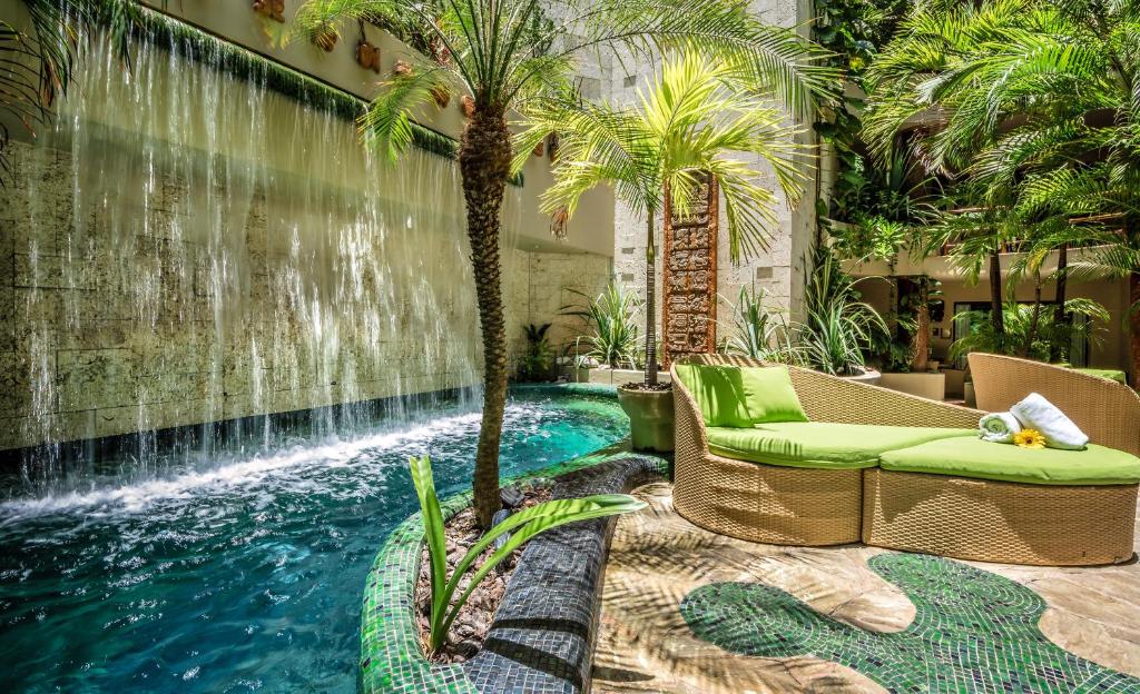 a pool in the middle of a patio with a chair and palm trees at Maya Villa Condo Hotel and Beachclub in Playa del Carmen