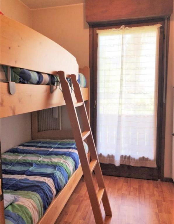 Łóżko piętrowe w pokoju z drabiną obok okna w obiekcie Condominio Ginepro w mieście Carisolo