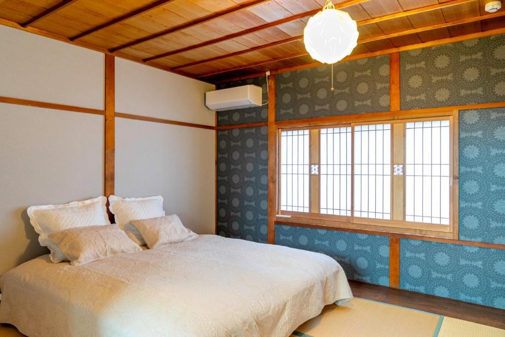 a bedroom with a bed and two windows at Folksy House / Vacation STAY 64171 in Izumo