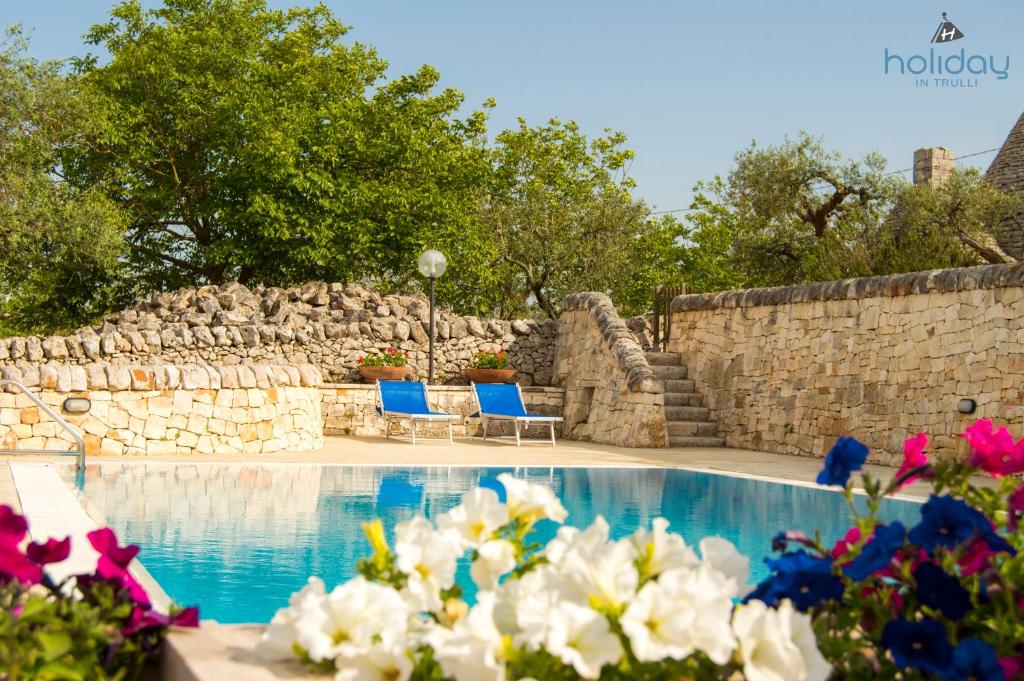 een zwembad met twee blauwe stoelen en bloemen bij I Trulli degli Ulivi in Locorotondo