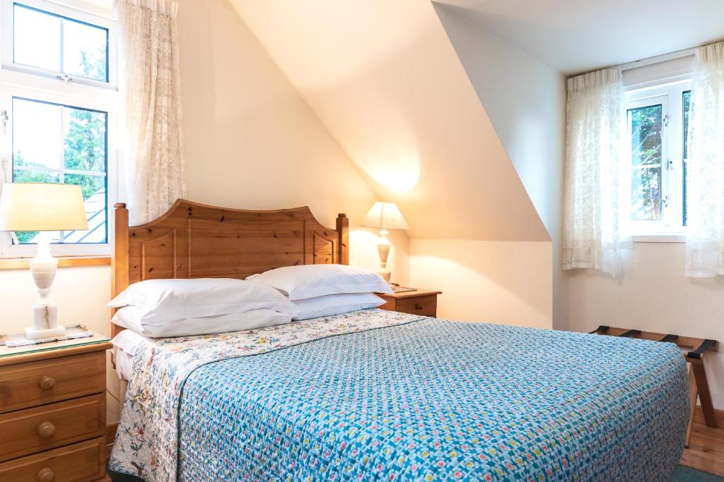 a bedroom with a bed with a blue comforter and two windows at An Bruachan B&B in Kenmare