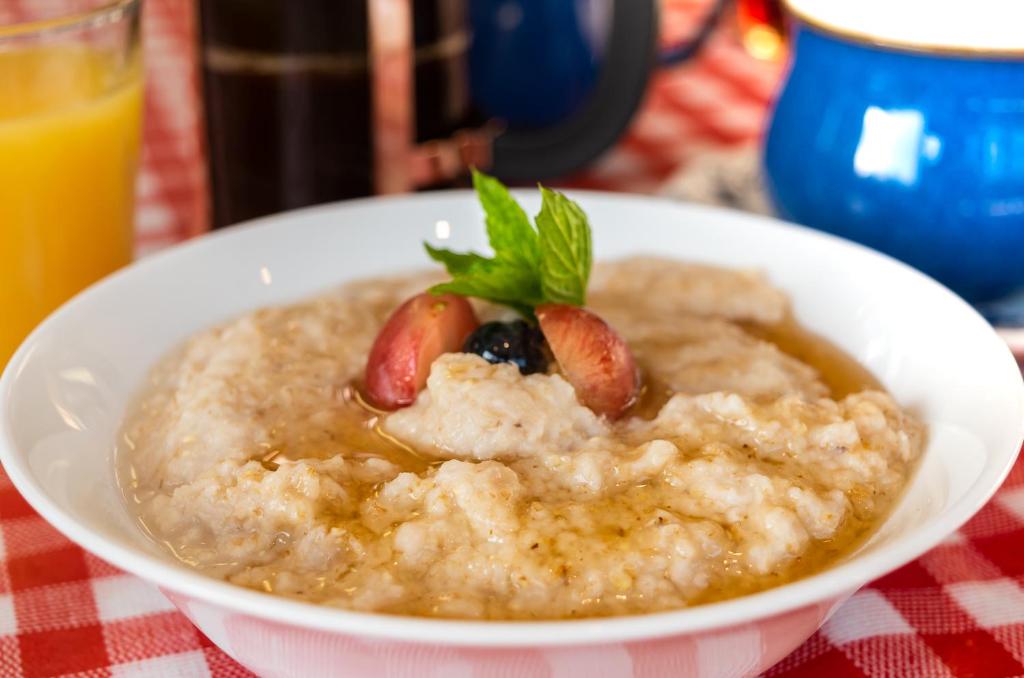 a bowl of oatmeal with strawberries and a green leaf at An Bruachan B&B in Kenmare