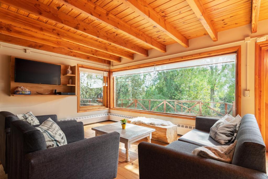 a living room with furniture and a large window at Bog Antilhue - Casa 2 cuartos in Villa La Angostura