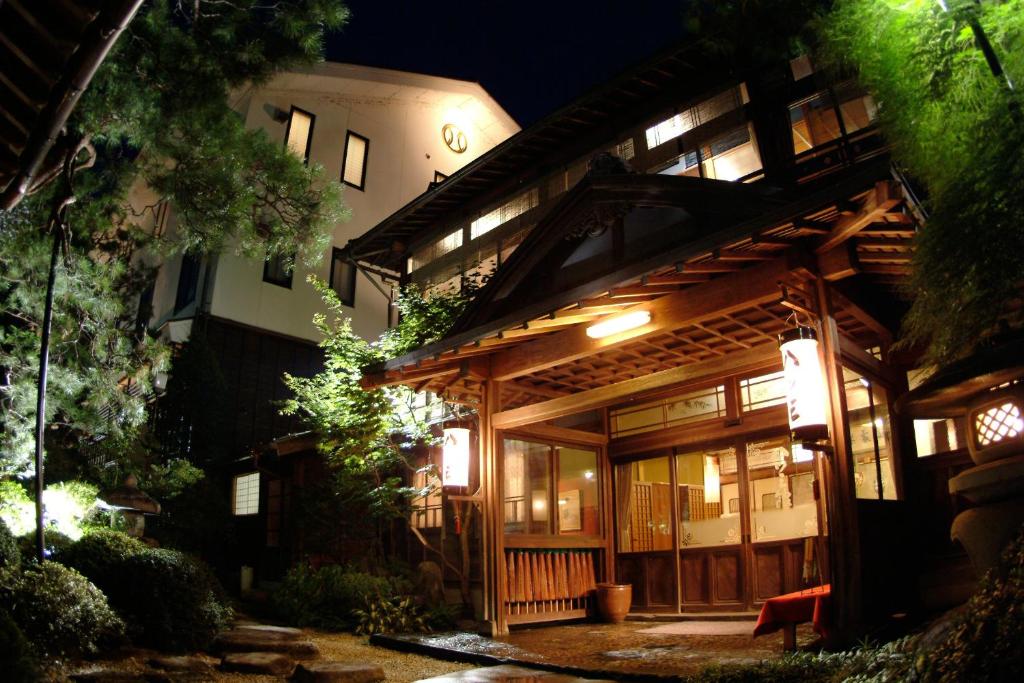 a large wooden building at night with lights at Yatsusankan in Hida