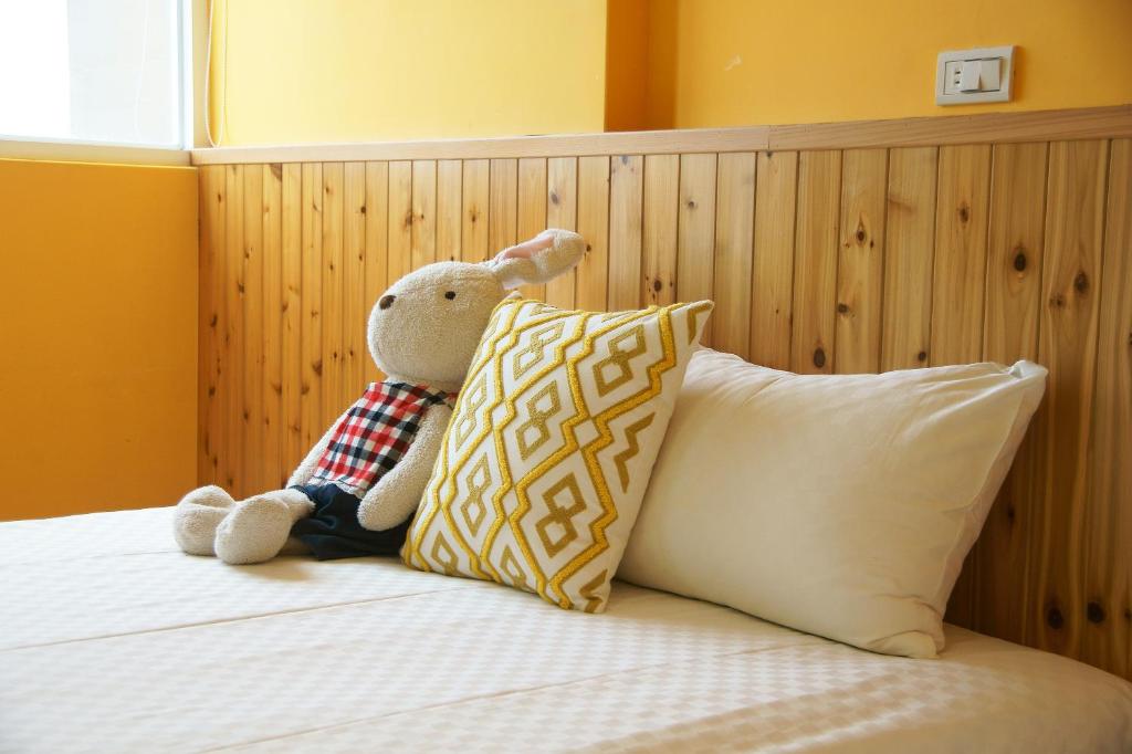 a teddy bear sitting on a bed with a pillow at Piau Po 21 Inn in Taitung City