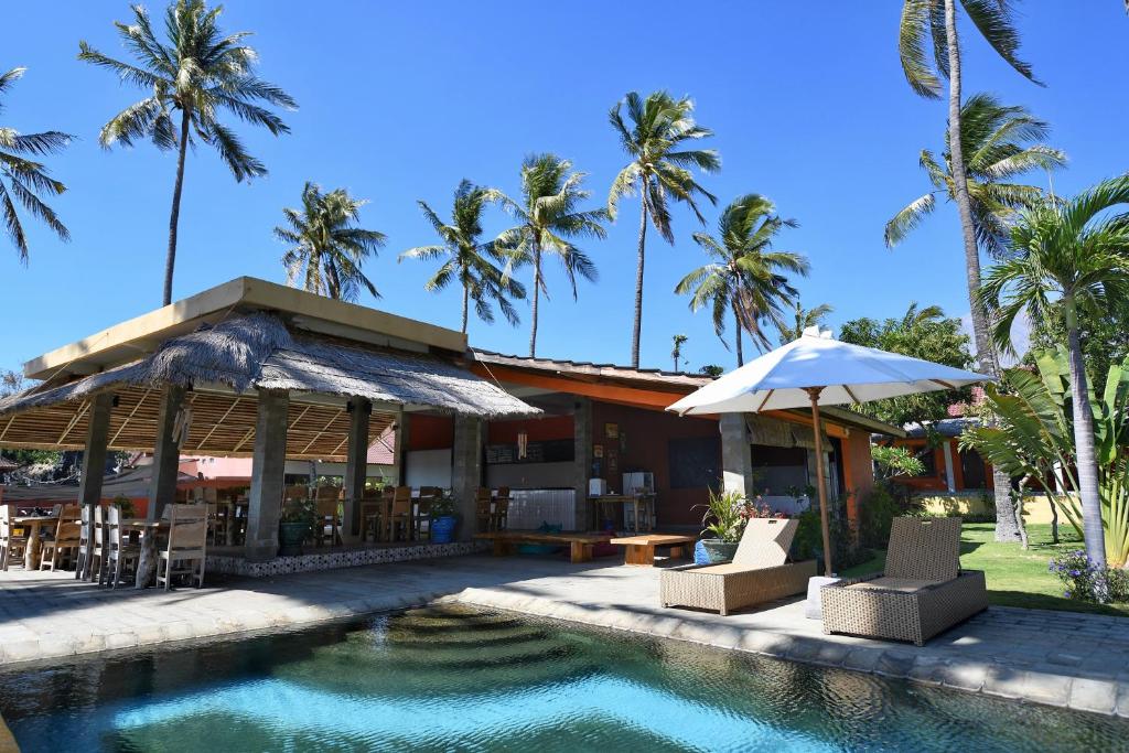 a resort with a swimming pool and palm trees at Pebble & Fins Bali Dive Resort in Tulamben