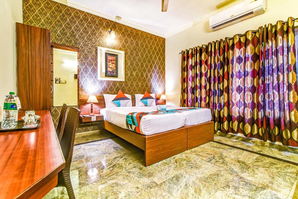 a hotel room with a bed and a desk and a table at FabExpress Nestlay Rooms in Chennai