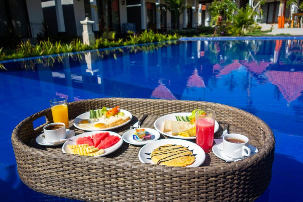 een dienblad met ontbijtproducten op een tafel bij het zwembad bij Sawit Garden Cottages in Nusa Penida