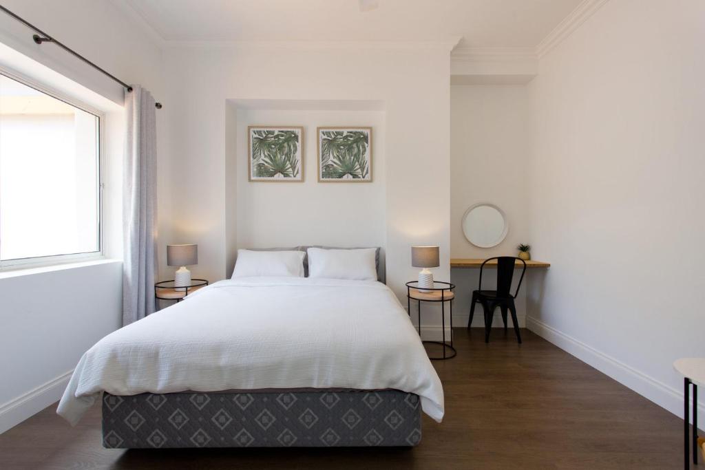 a white bedroom with a large bed and a window at Koala at White Gum Lodge in Fremantle