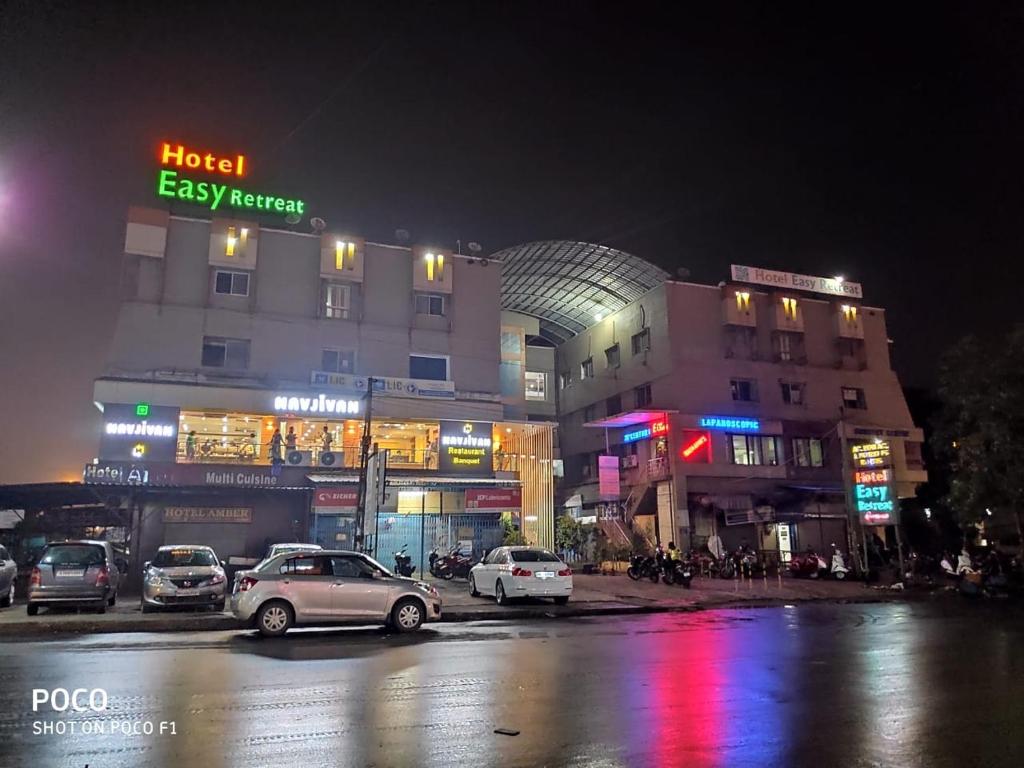 a city street at night with cars parked in front of buildings at Hotel Easy Retreat in Vapi