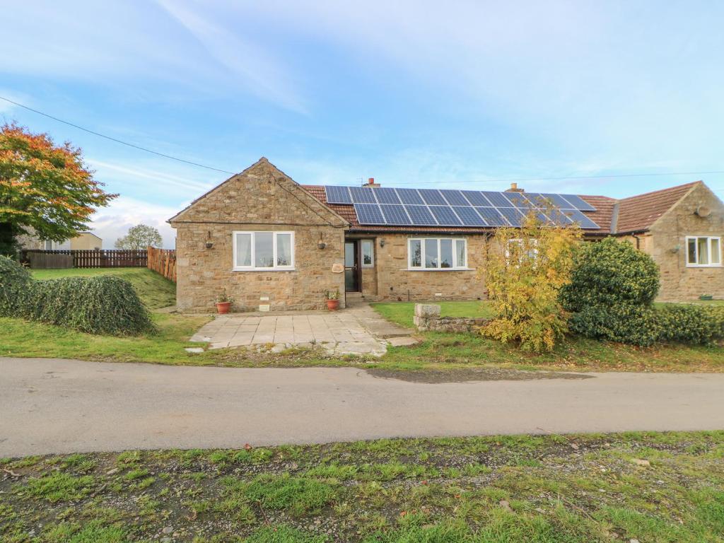 a brick house with solar panels on the roof at Barforth Hall Lodge in Richmond