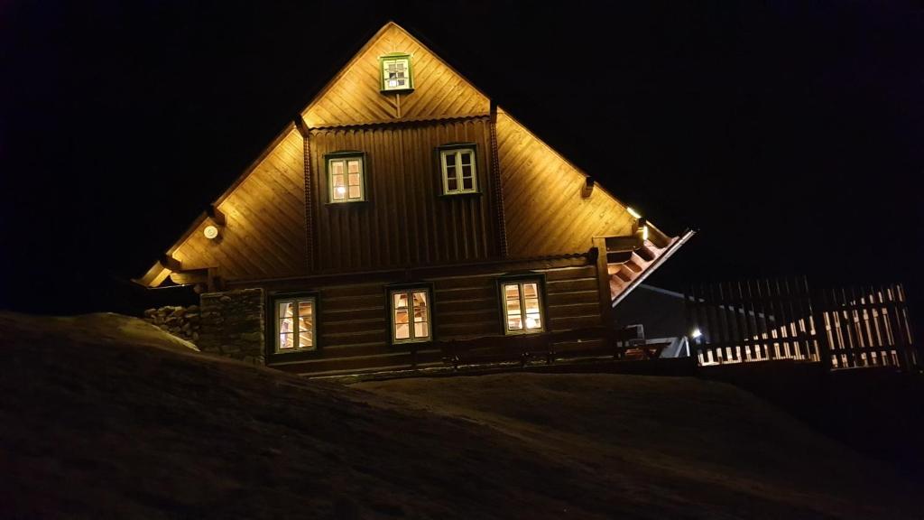 a large wooden house at night with lights on it at Chalupa MODŘÍN in Horní Maršov