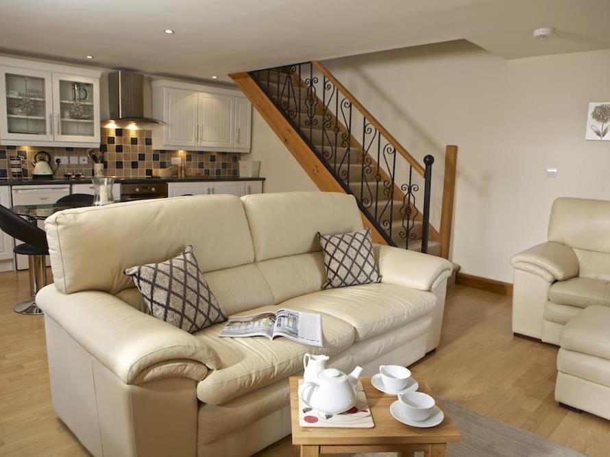 a living room with a white couch and a staircase at Meadow View in Ivybridge