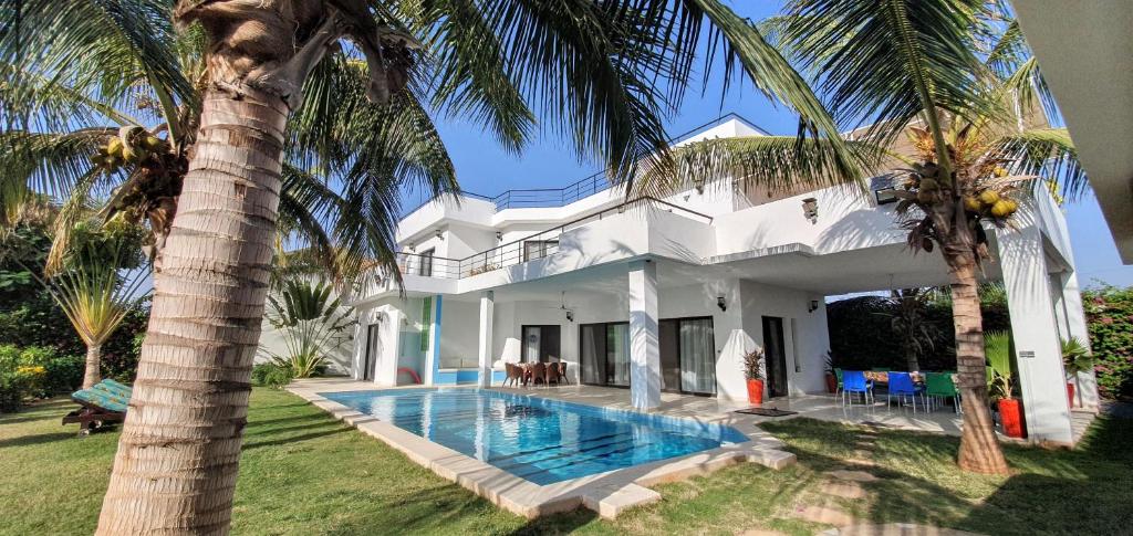 ein weißes Haus mit einem Pool und einer Palme in der Unterkunft La Maison Blanche à Ngaparou, splendide villa contemporaine in Ngaparou