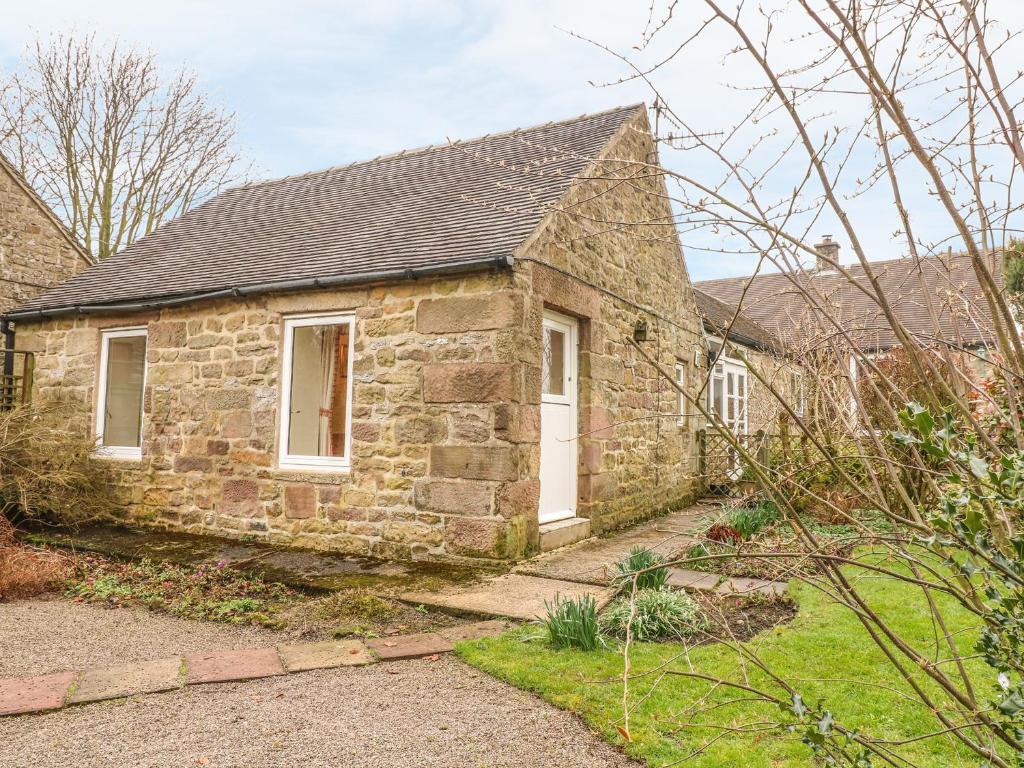 an old stone house with a white door at Barn Croft Cottage in Matlock