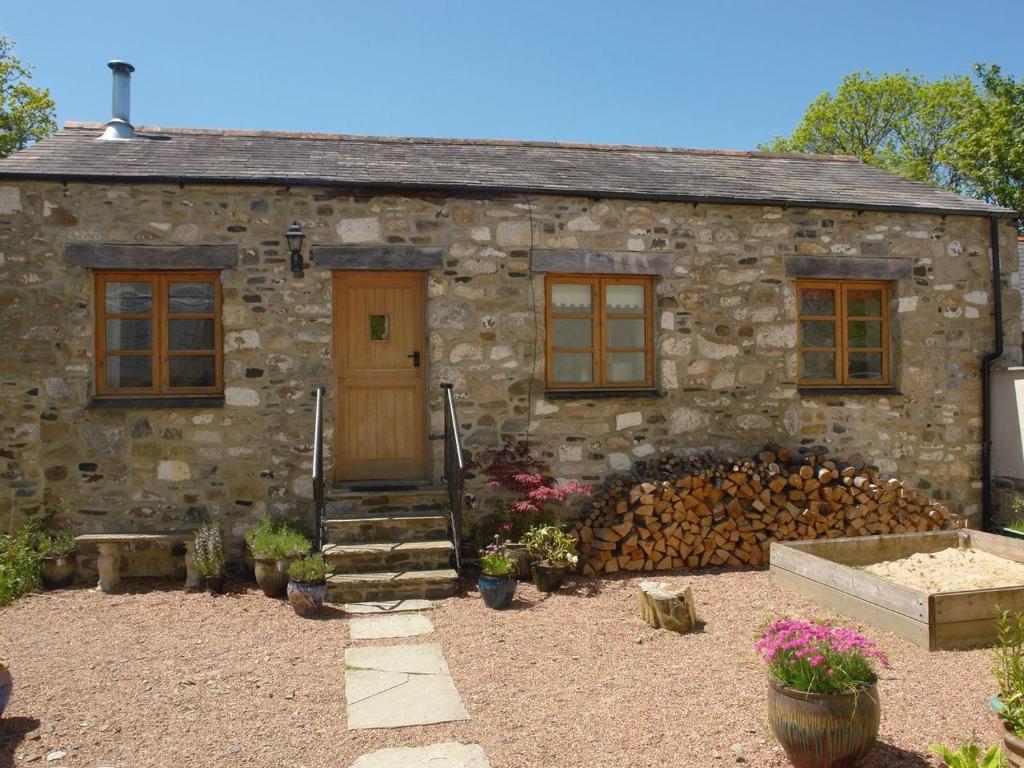 a stone house with a wooden door and a yard at Mill House Barn in Okehampton
