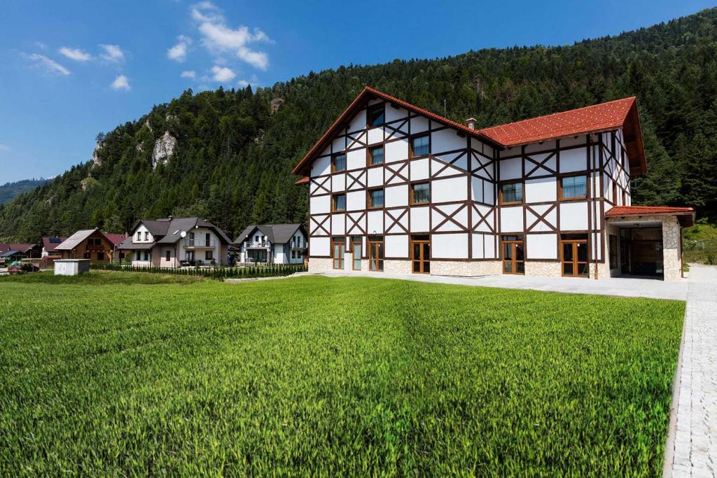 a large building with a green field in front of it at Rezort Gothal Apartmány a Penzióny in Donovaly