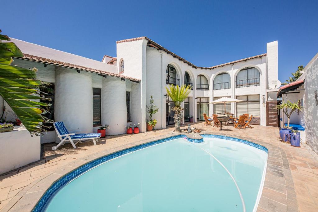 a swimming pool in front of a house at Big Blue Accommodation in Bloubergstrand