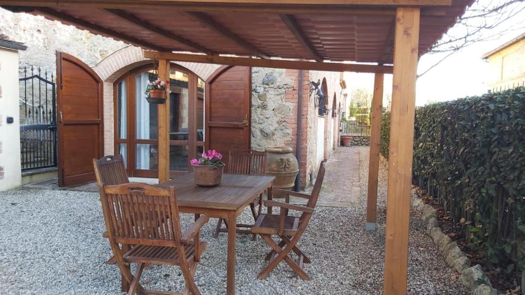 drewniany stół i krzesła pod drewnianą pergolą w obiekcie La Limonaia Country House w mieście Monteriggioni
